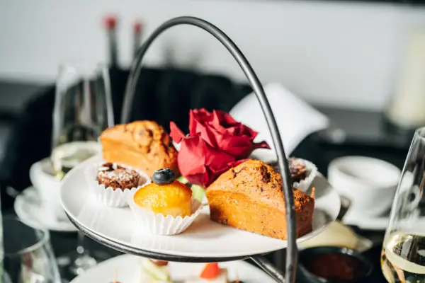 A plate of pastries next to a rose on a table.