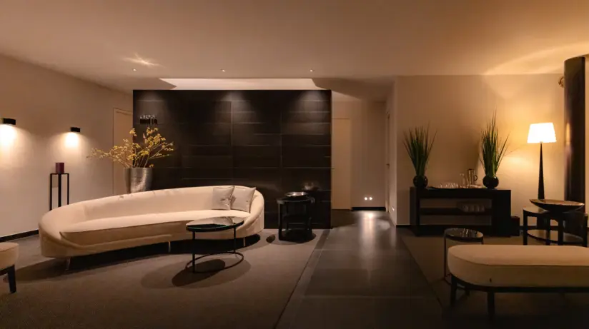 An elegant SPA room featuring a white couch against a black wall, complemented by a coffee table and minimalist decor.