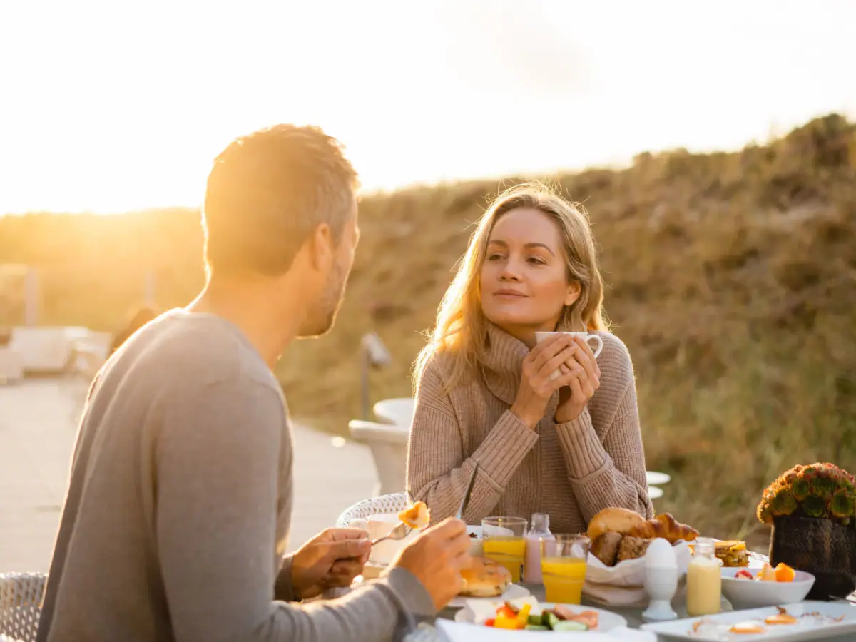 Couple enjoying breakfast outdoors in the dunes at an A-ROSA resort.