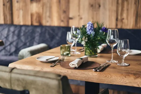 A table with wine glasses and napkins, decorated with a floral centerpiece.