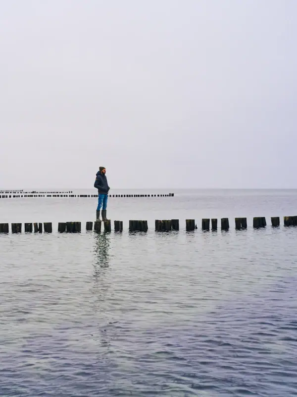 A person standing on a log in the water under a clear sky.