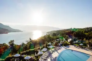 A swimming pool with parasols and sun loungers by the water’s edge.