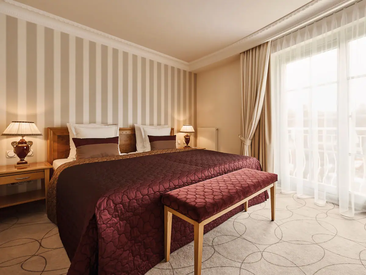 Ein Bett mit einer Bank in einem Zimmer mit gestreiften Wänden.
