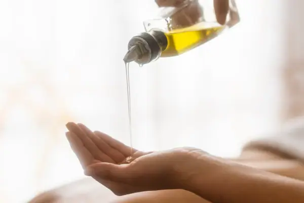 Eine Person gießt Öl auf ihre Hand.