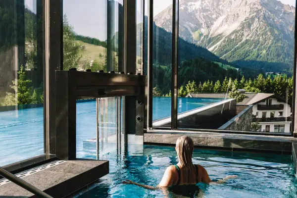 Außenpool Eine Frau in einem Pool mit Bergen im Hintergrund.