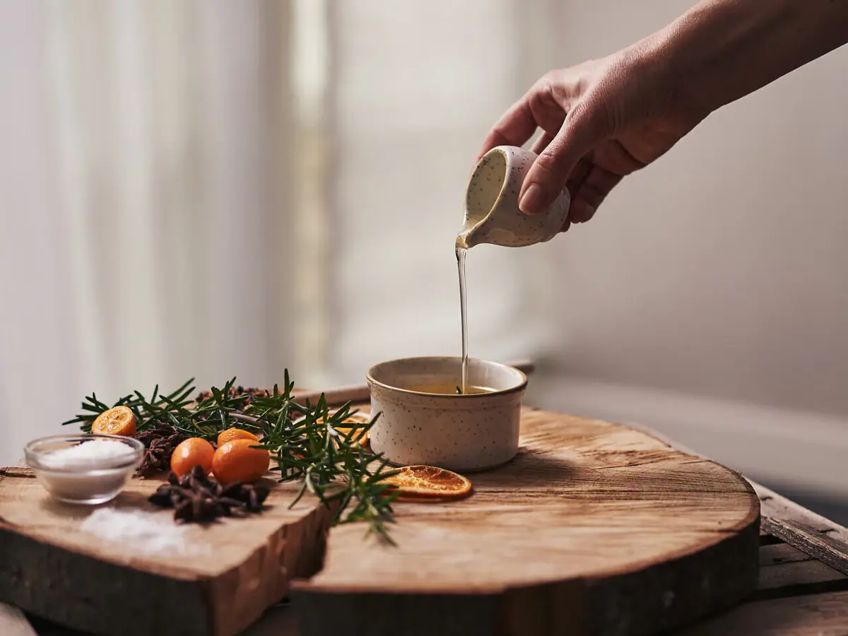 A person pouring liquid into a bowl while cooking indoors.