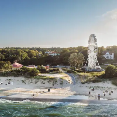 Ferris wheel on a beach with a clear sky and water in the background.