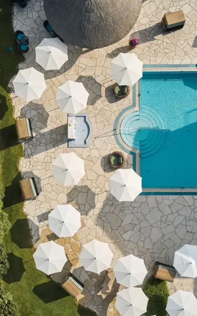 Outdoor pool surrounded by parasols and sun loungers.