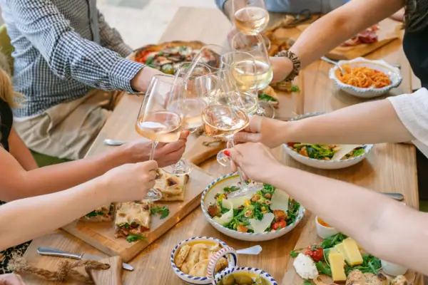 A group of people holding wine glasses, gathered around a table.