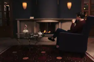 A man is sitting in an armchair, drinking from a cup.