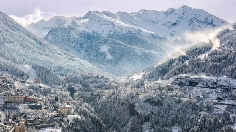 Snow-covered mountain landscape with a village in the valley and many snow-covered trees.