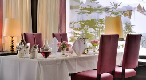 A table with a white tablecloth is in a restaurant.