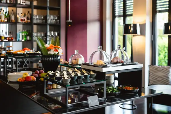 Buffet table with a variety of food and bottles on a countertop indoors.