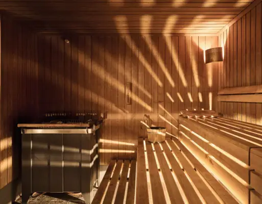 Wooden sauna with sunlight filtering through the walls.