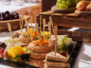 A tray with sandwiches, fruit and various dishes on a table.