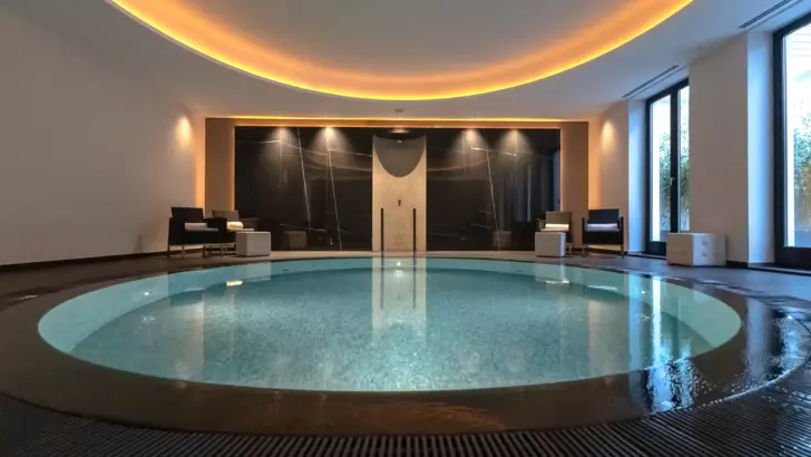 An indoor pool with a large round body of water, surrounded by elegant interior design elements.