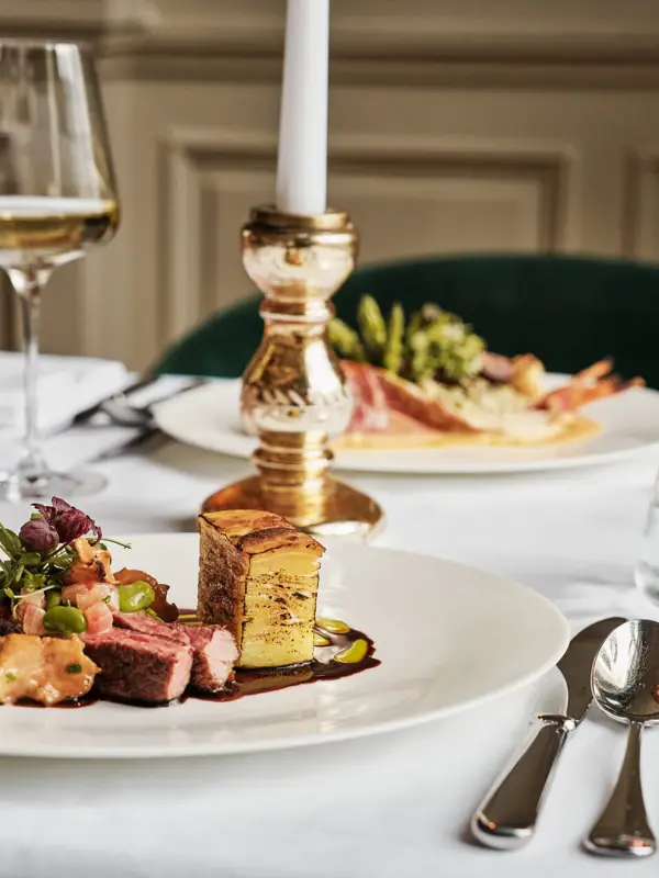A plate of food with a wine glass on a table.