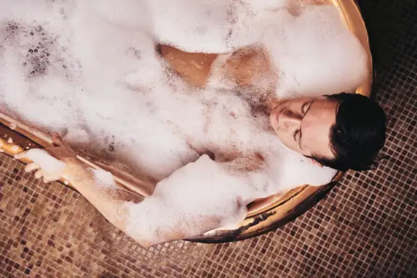 Frau entspannt in der goldenen Kaiserwanne mit Schaum und Wellness-Details im A-ROSA Ostseehotel Kühlungsborn