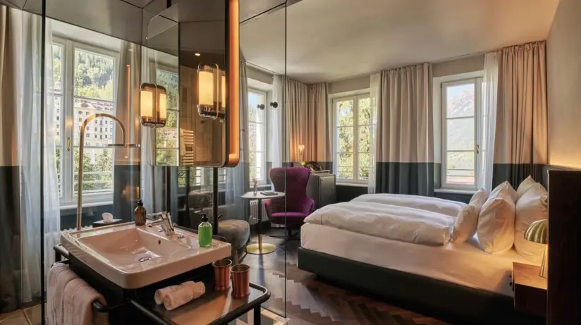 A cozy bed with pillows and a bedside lamp in a hotel room.