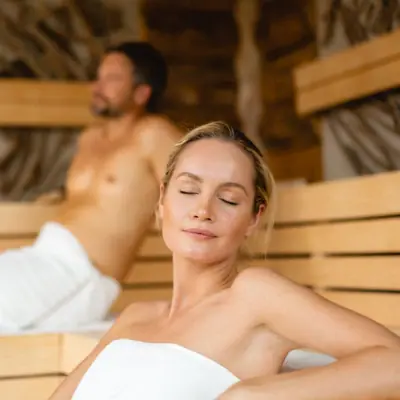 sauna and relaxation A woman sits in a sauna, a man in the background.
