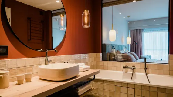 Modern bathroom featuring a sink with a tap and a bathtub, complemented by tiled walls and a mirror.