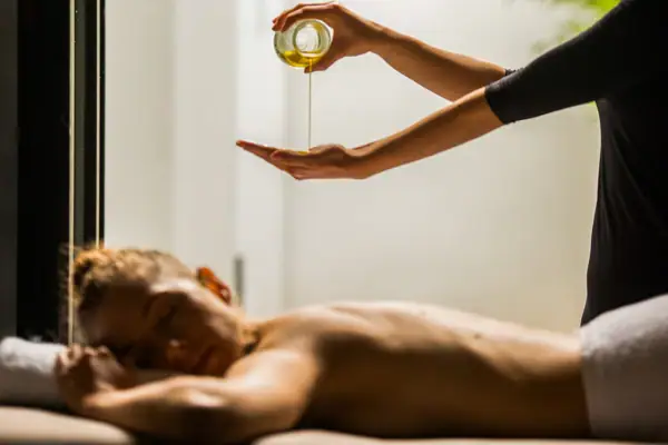 A person pouring oil into another person's hand indoors.