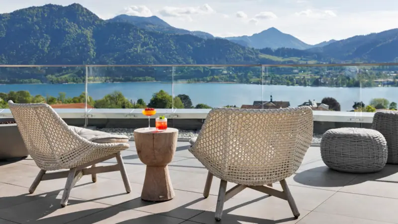 A table and chairs on a patio overlooking a body of water with mountains in the background.