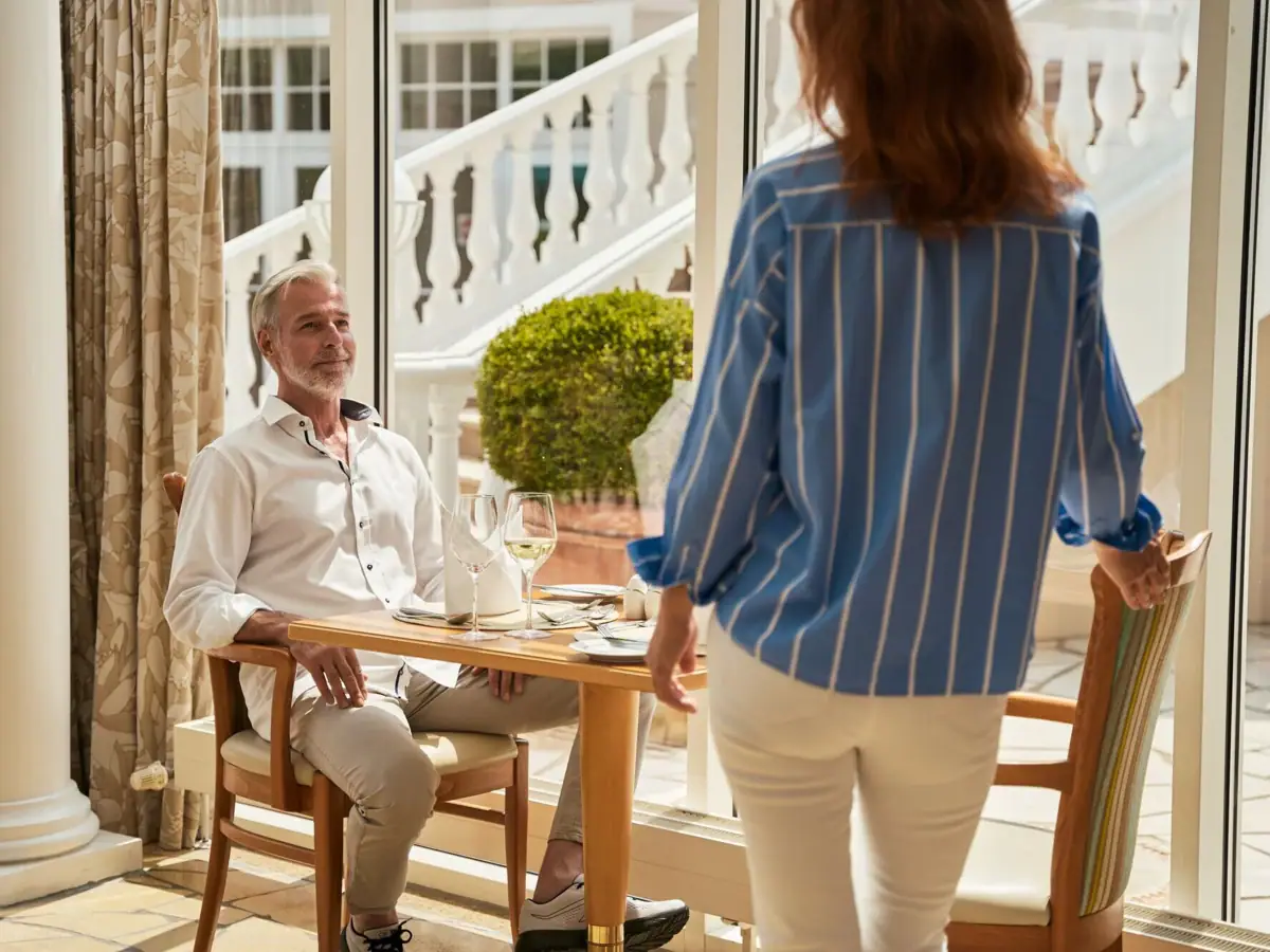 A woman standing next to a man at a table.