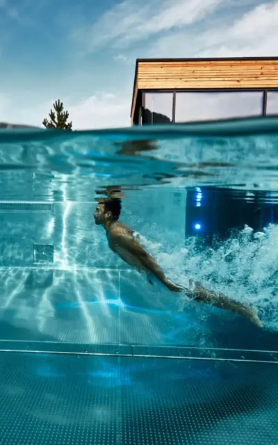 Man swimming underwater in an outdoor pool