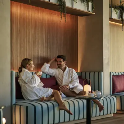 A man and a woman in bathrobes are sitting on a sofa.
