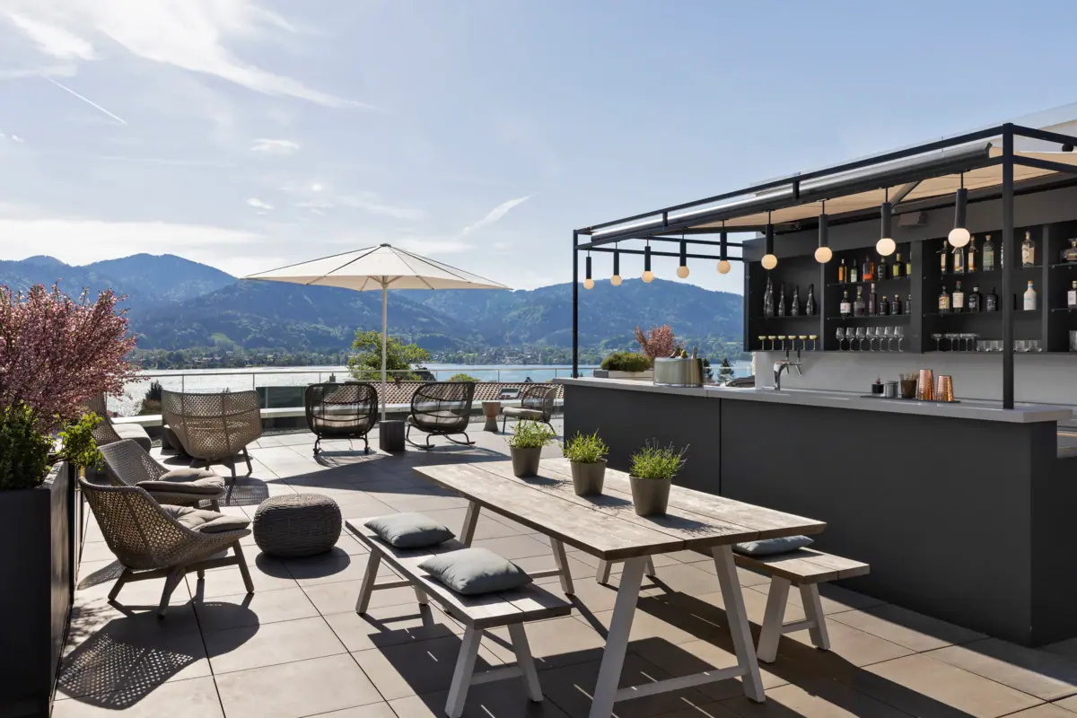 Rooftop terrace with bar, chairs, table and parasol.