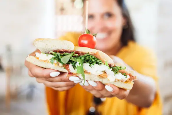 Eine Frau hält ein Sandwich.