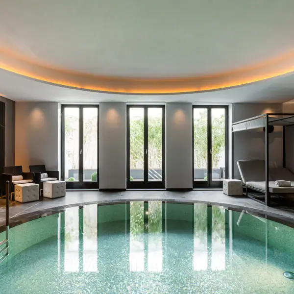 Indoor pool with a bed and chairs.