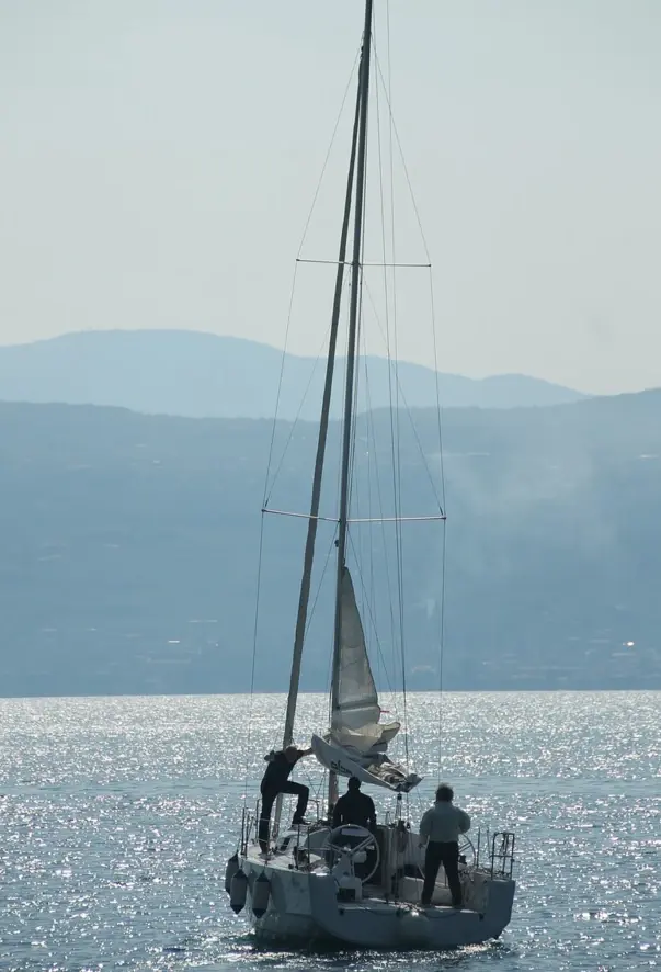 Three people on a sailing boat on the water.