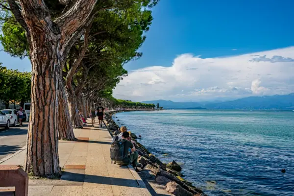 Peschiera del Garda A group of people are sitting on the bank of a body of water.