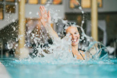 A woman swirls water in the pool, laughing.