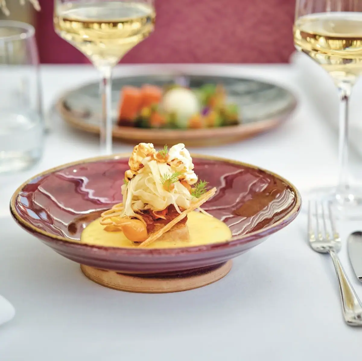 A plate of food with a wine glass on a table.
