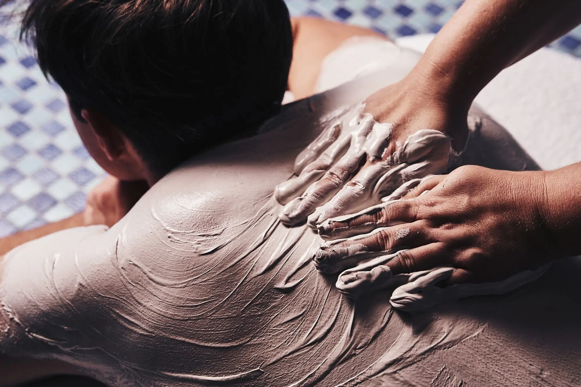 Massage A person's hands applying a white substance on another person's back.