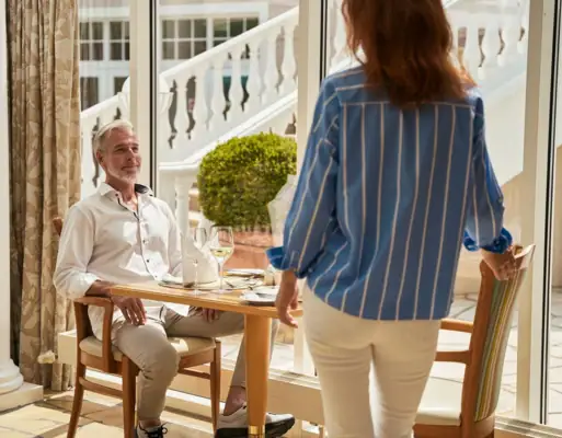 A woman standing next to a man at a table.