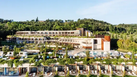 A modern designed hotel blends elegantly into a natural landscape. The terraced architecture offers sweeping views from every floor and integrates green spaces on the rooftops. Two pools and carefully landscaped gardens invite guests to relax, while the surrounding greenery of trees provides a calming backdrop.