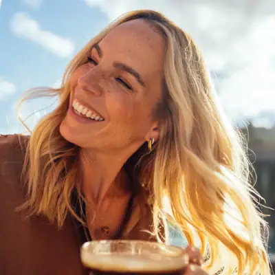 A woman smiles with a cup of coffee.