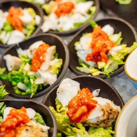 A group of small black bowls with various dishes.