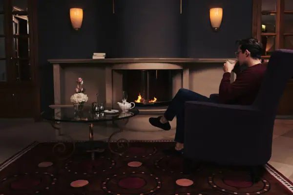 A man sitting in a chair drinking from a cup indoors.