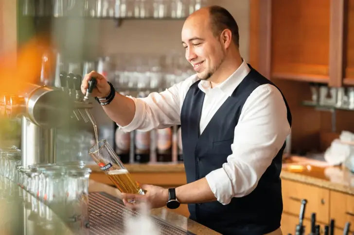 Man draws beer from a tap in a bar.