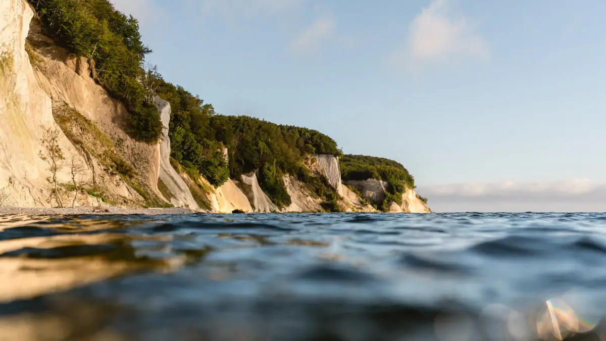 Ein Gewässer mit einer Klippe und Bäumen.