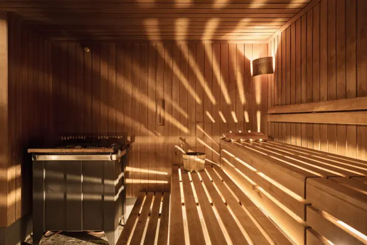 Wooden sauna with sunlight streaming through the walls.