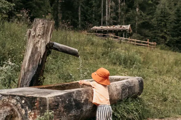 A child is drinking from an outdoor drinking fountain.
