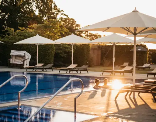 Ein Pool mit Sonnenschirmen und Liegestühlen.