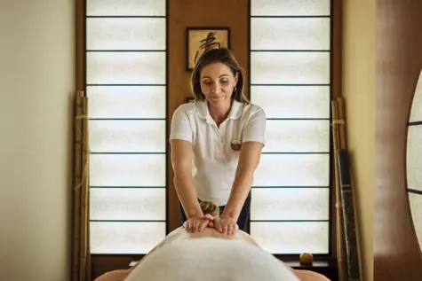 A woman giving a back massage in a serene indoor setting.