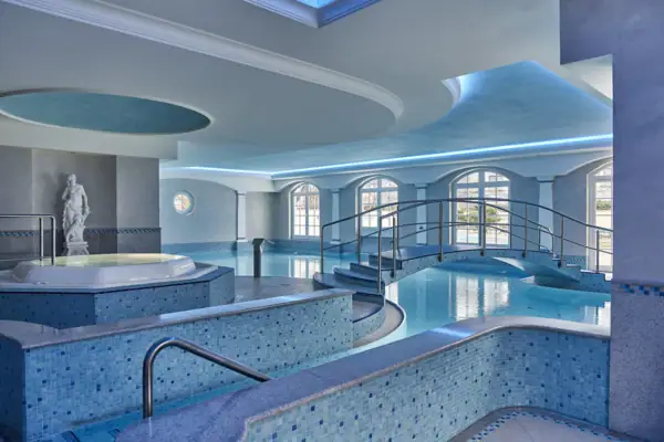 A large indoor pool with a hot tub and stairs.